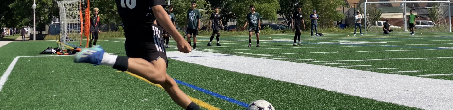 Soccer player kicks ball on turf field.